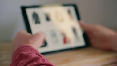 Adamın elinde tablet, internetten alışveriş giysileri.