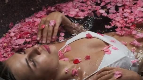 Молода жінка в квітковій ванні. Спа-релаксація та лікування — стокове відео