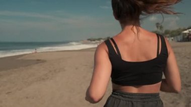 Kumlu sahil şeridinde koşan sporcu kadın