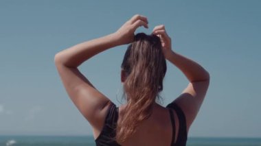 Tanınmayan dişi at kuyruğu bağlıyor ve deniz manzarasının tadını çıkarıyor.