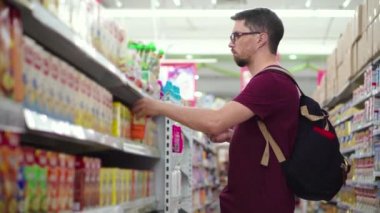 Genç adam süpermarketten bebek maması alıyor.