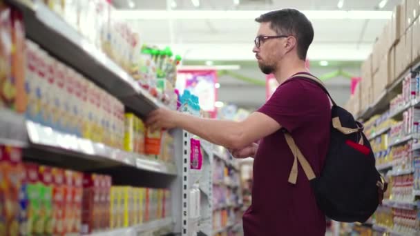 若い男はスーパーマーケットでベビーフードを買っている — ストック動画