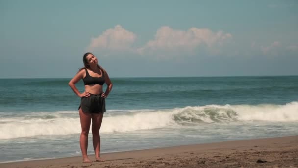 Привлекательная женщина тренируется на песчаном берегу океана — стоковое видео