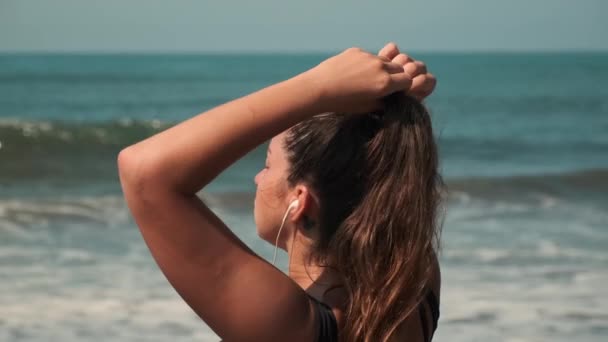 Woman is enjoying music in earphones and ocean shore — Stock Video