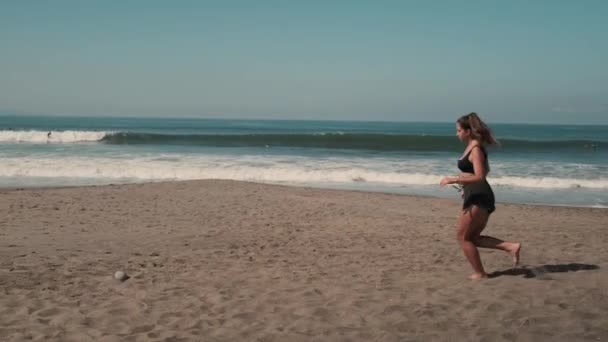 Όμορφη γυναίκα τρέχει κατά μήκος της αμμώδους ακτής του ωκεανού — Αρχείο Βίντεο