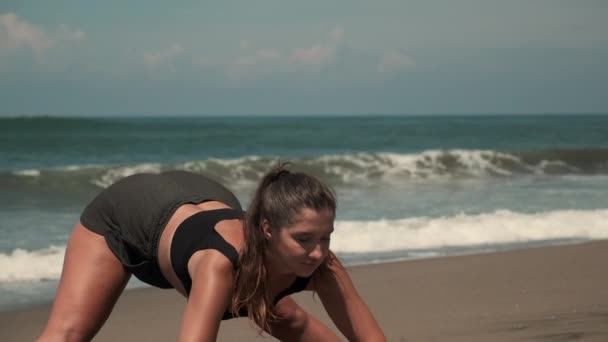 Csábító hölgy nyújtózkodik az óceán homokos partján. — Stock videók