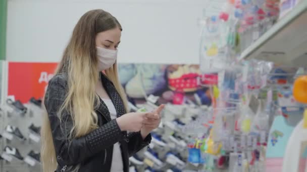 Maskeli kadın çocuk eşyaları bölümünde alışveriş yapıyor. — Stok video