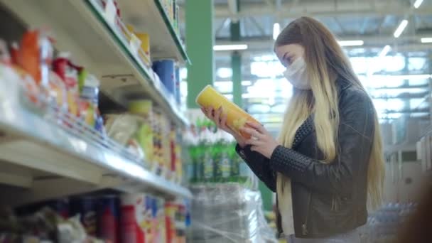 Tıp maskeli genç bir kadın marketten cips alıyor. — Stok video