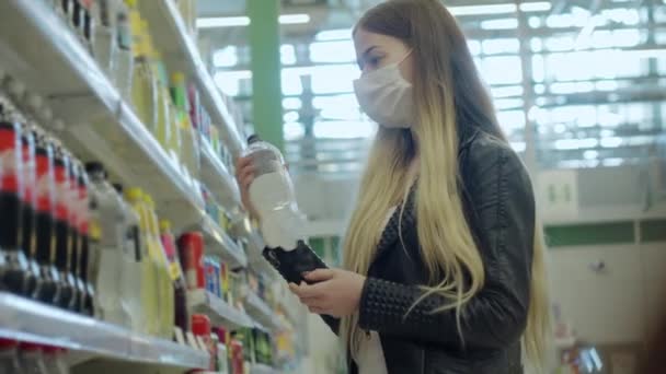 Jovem fêmea em máscara médica comprando bebidas de refrigerante no shopping — Vídeo de Stock