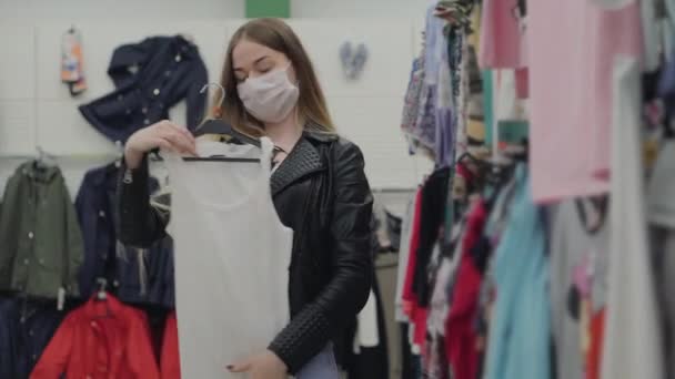 Compras na pandemia de coronavírus, mulher com máscara facial na loja de roupas — Vídeo de Stock