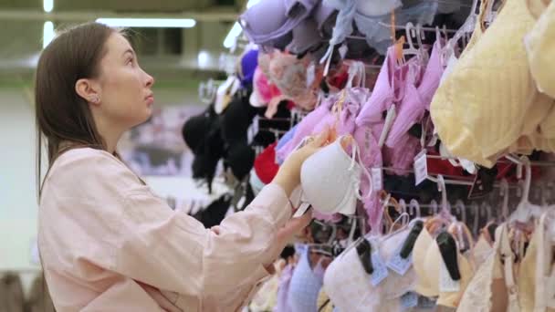 Jeune femme achète un soutien-gorge dans un magasin de sous-vêtements — Video