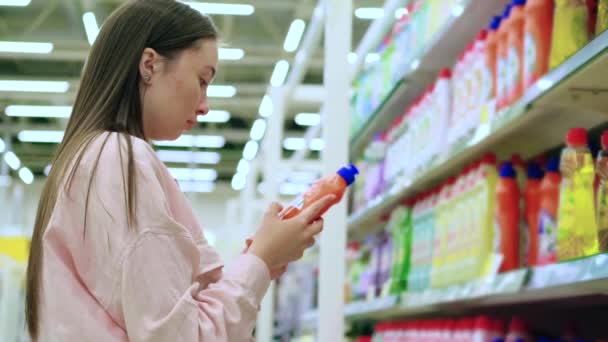 Comprador femenino está leyendo etiquetas en líquido de lavado de platos — Vídeos de Stock