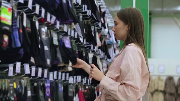 Femme shopper prend hommes chaussettes de rack dans supermarché — Video