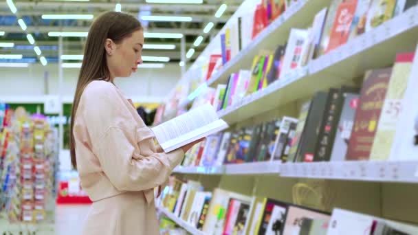 Girl doing the shopping in book store — Stock Video