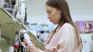 Kadın dükkanda blender seçiyor.