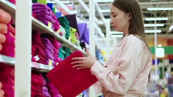 Junge Frau kauft im Supermarkt ein Badetuch — Stockvideo