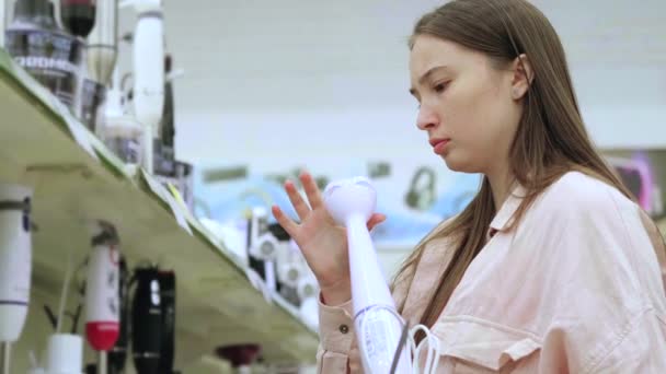 Jeune femme essayant de choisir le meilleur mélangeur dans le magasin — Video