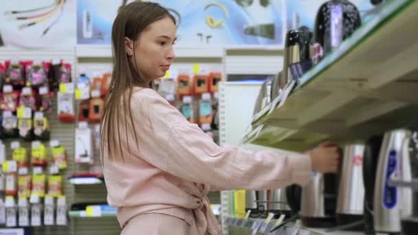 Vrouwelijke shopper in de winkel, kiezen voor elektrische thee waterkoker — Stockvideo