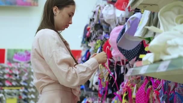 Comprador femenino está eligiendo traje de baño de los niños en la tienda — Vídeos de Stock