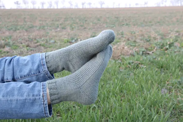 a man in a green sweater and a socks on a background of a field of grass in the spring