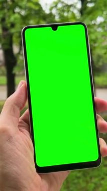 Yeşil ekranlı bir telefonu elinde tutan adam. Akıllı telefon yeşil ekran arkaplanı.