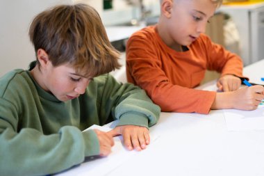 İki genç çocuk özenle kendi sanat projeleri üzerinde çalışıyor. Odaklanma ve yaratıcılık gösteriyorlar.