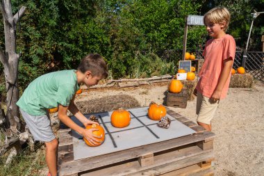İki genç sonbahar boyunca balkabağı tarlasında balkabağı tik-tac-toe oyunu oynuyorlar.