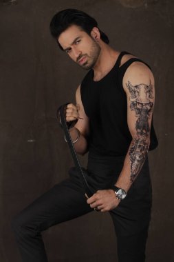 Gri arkaplanda dövmesi olan genç bir adam.