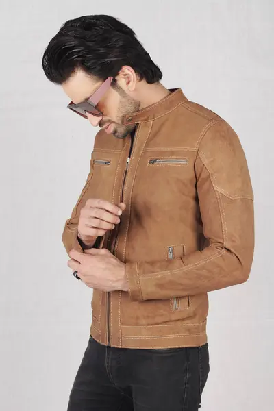 Stüdyoda poz veren güneş gözlüklü ve ceketli model.