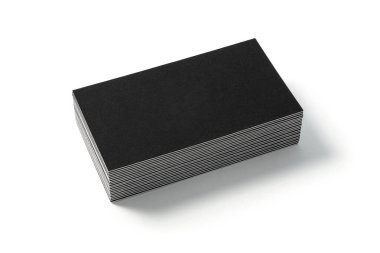 Beyaz arkaplanda boş bir siyah kartvizit var. Yan görüş. Standart boy. Kişisel reklam veya kurumsal tasarım için desenli karton yığını. 