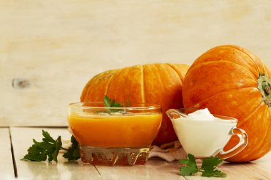 kabaklar ve beyaz ahşap masa maydanoz yaprakları ile ev yapımı kabak krem çorbası. balkabağı çorbası ekşi krema ve bir cam kase kabak çekirdeği ile. kabak kremalı çorba