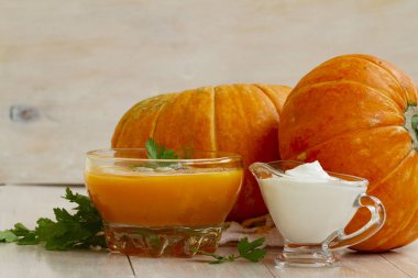 kabaklar ve beyaz ahşap masa maydanoz yaprakları ile ev yapımı kabak krem çorbası. balkabağı çorbası ekşi krema ve bir cam kase kabak çekirdeği ile. kabak kremalı çorba