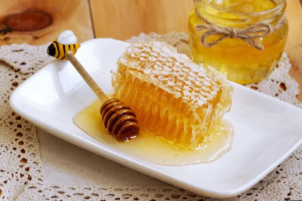 sıvı bal, rustik ahşap masada taze petek. Dantel keten peçete üzerinde plaka üzerinde taze petek. sağlıklı organik doğal ürünler. Ahşap dispenseri ve bal tarak yakın çekim ile taze bal kavanozu.