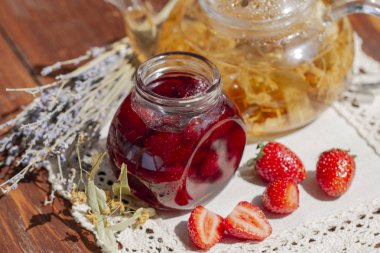 Taze çilek ve çaydanlık ıhlamur lavanta çayı ve dantel keten peçete ve ahşap masa üzerinde çiçekler ile Çilek reçeli. Çilek ile taze ev yapımı çilek reçeli. Çilek confiture ile Cam kavanoz
