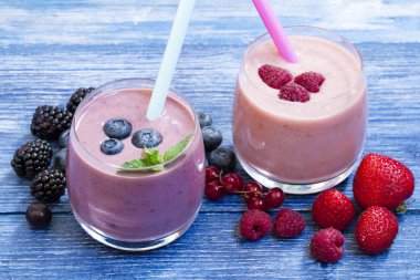 Rustik mavi arka plan taze yaban mersini ve çilek ile ev yapımı smoothie. kilo kaybı kavramı. mavi ahşap masa üzerinde yaban mersini yüzlü. taze çilek ile milkshake. berry jogurt smoothie.