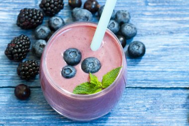 Rustik turkuaz arka plan üzerinde taze yaban mersini ile ev yapımı smoothie. mavi ahşap masa üzerinde yaban mersini yüzlü. taze çilek ile milkshake. cam berry jogurt smoothie, kopya alanı. üst görünüm.