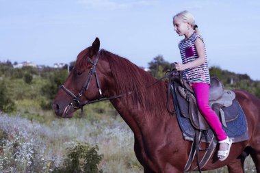 Gün batımında bir köy yolunda kahverengi bir ata binen sevimli genç kız. Çocuk sessizce bir aygır üzerinde seyahat ediyor. Kız güvenle bir çiçeklenme alanında atı kontrol eder. Çocuk yaz spor kampı.