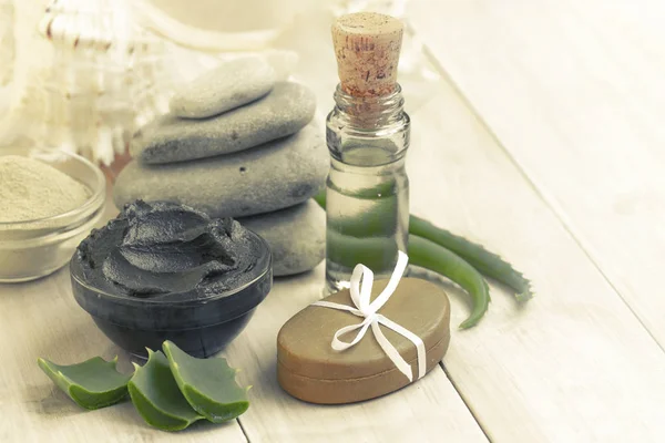 Preparing cosmetic mud mask in glass bowl with aloe vera and essential oil on white background. Natural cosmetics for home or salon treatment. cosmetic mud with hand made soap with spa products.