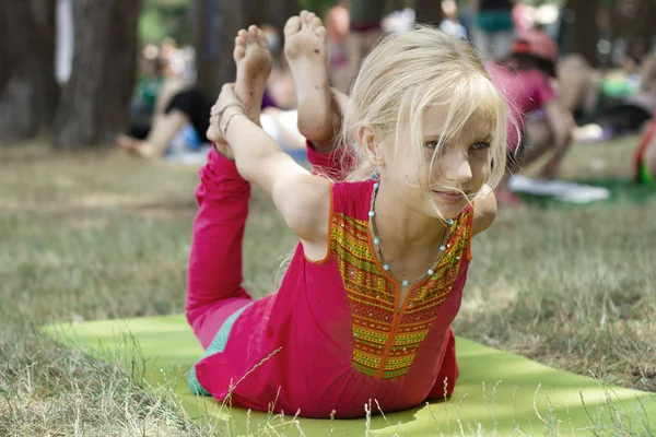 Kleine süße kaukasische Mädchen praktizieren Yoga-Pose auf Matte im Park. gesundes, bewegungsorientiertes Konzept. Kinder Yoga Konzept. Mädchen übt Yoga. Kind macht Übungen im Park. Gesunder Lebensstil. — Stockfoto