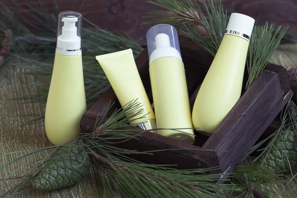 blank bottle packaging with natural cosmetic cream, serum, skincare, lotion, tonic with forest coniferous branches and cones on wooden background. beauty and spa concept. bio organic product.