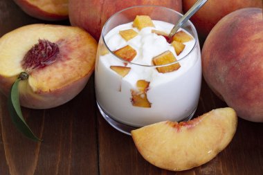 şeftali yoğurt, tatlı yaz tatlısı. Taze meyveli lor tatlısı. Sağlıklı, vitamin açısından zengin kahvaltı. ahşap bir arka plan üzerinde taze şeftali dilimleri ve bütün şeftali ile yoğurt. yakın çekim.