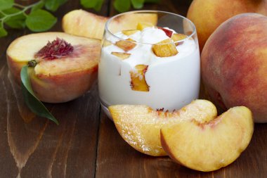 şeftali yoğurt, tatlı yaz tatlısı. Taze meyveli lor tatlısı. Sağlıklı, vitamin açısından zengin kahvaltı. ahşap bir arka plan üzerinde taze şeftali dilimleri ve bütün şeftali ile yoğurt. yakın çekim.