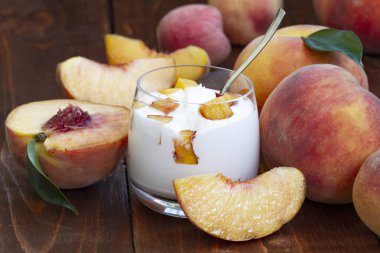 şeftali yoğurt, tatlı yaz tatlısı. Taze meyveli lor tatlısı. Sağlıklı, vitamin açısından zengin kahvaltı. ahşap bir arka plan üzerinde taze şeftali dilimleri ve bütün şeftali ile yoğurt. yakın çekim.