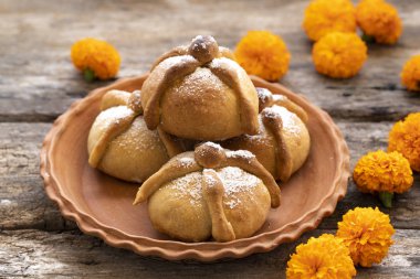 Meksika kutlaması, ölüm ekmeği. Ölü ekmekli Meksika partileri ve gri taşlı arka planda kadife çiçekleri. Geleneksel Ölü Pan de Muerto Meksika Ekmeği .