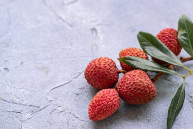 Gri arka planda yaprakları olan Lychee. Tropik meyve