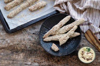 Yeni pişirilmiş ev yapımı ekmek çubukları ve ev yapımı mayonez, humus ya da ahşap masadaki beyaz soslu susamlı ekmek tepsisi. Köy yemekleri. Kırsal tarzda. en üstteki görünüm