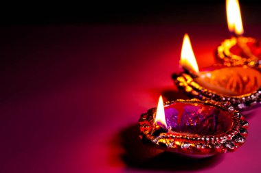 Hindistan Işık Festivali için Mutlu Diwali mor arka planında yanan diya, kopyalama alanı