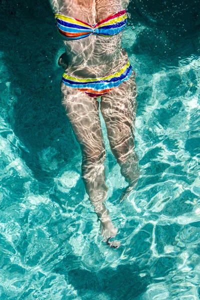 Young woman swimming and relaxing in the water basin.