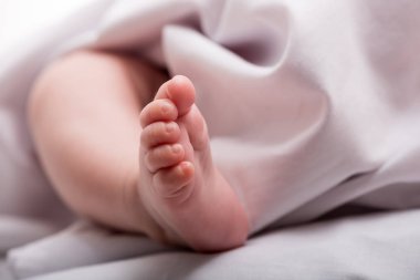 Beyaz bir battaniyenin üzerinde yeni doğmuş bir bebek. Bebek ayakları yakın plan.