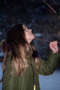 Kız akşam gökyüzünde kar yağışı sırasında örnek alıyor.
